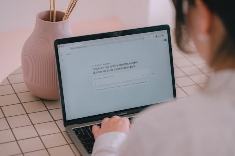 Woman typing on a laptop with a vase nearby