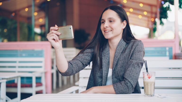Woman taking a selfie at an outdoor cafe.