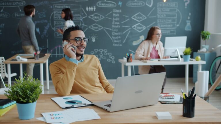 Man talking on phone in modern office with team